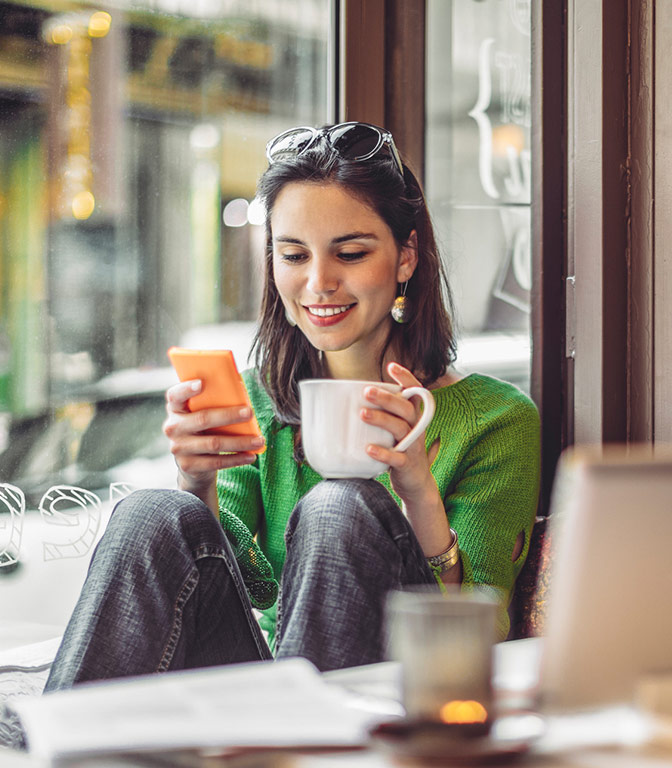 Person in a coffee shop checking her account on her phone.